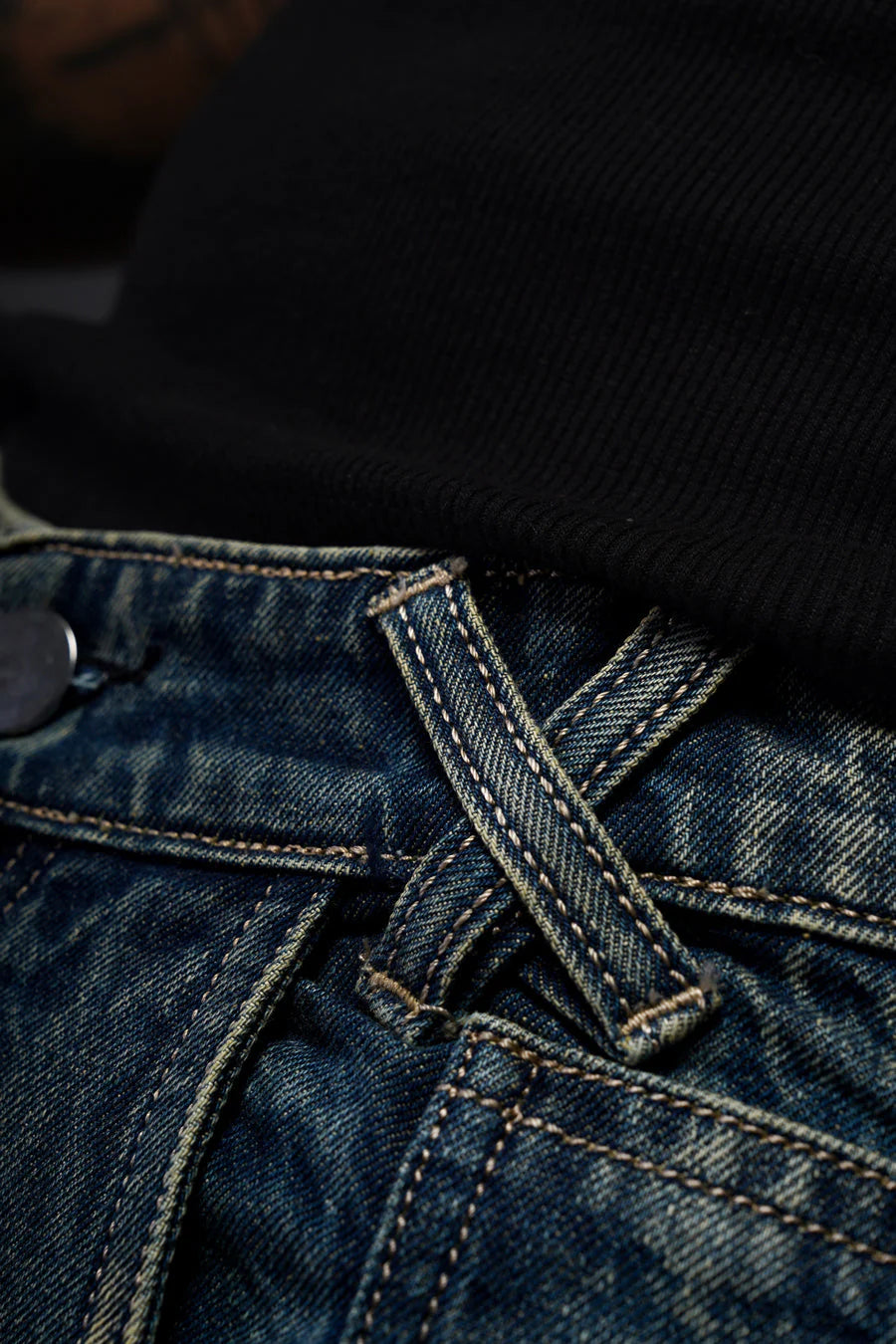 Denim jeans waistband with button fly, gold stitching, blue wash with distressed seams.