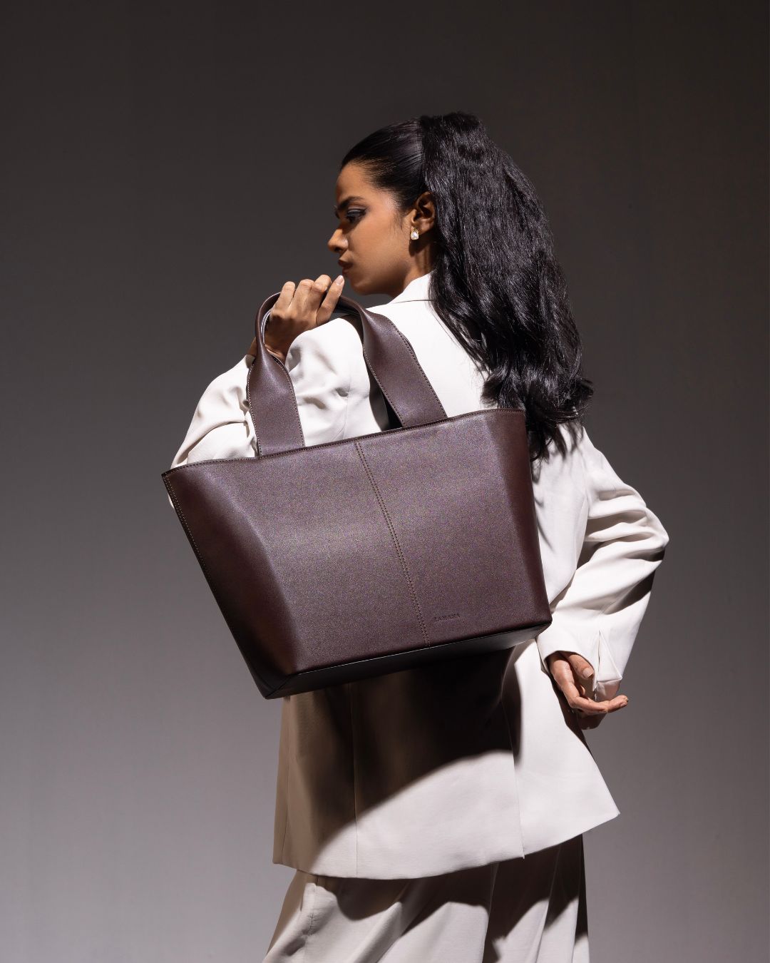 Dark brown tote bag with double handles, stitched front panel, and structured shape