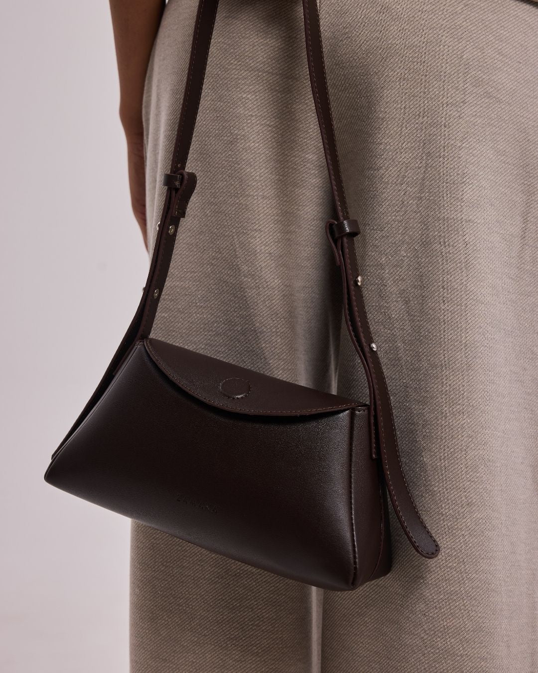 Dark brown leather hobo bag close-up with button strap details and curved front