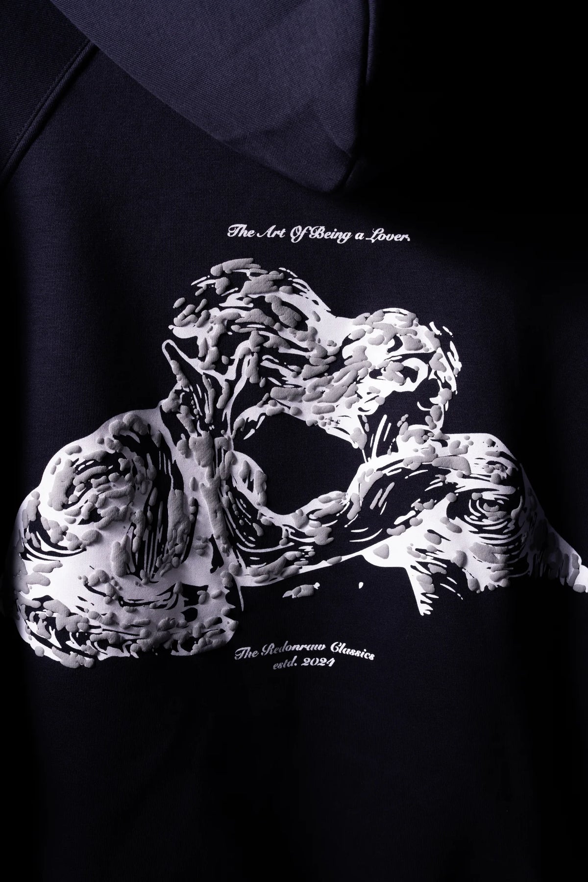 Dark navy hoodie with white sculpted graphic and small slogan text beneath