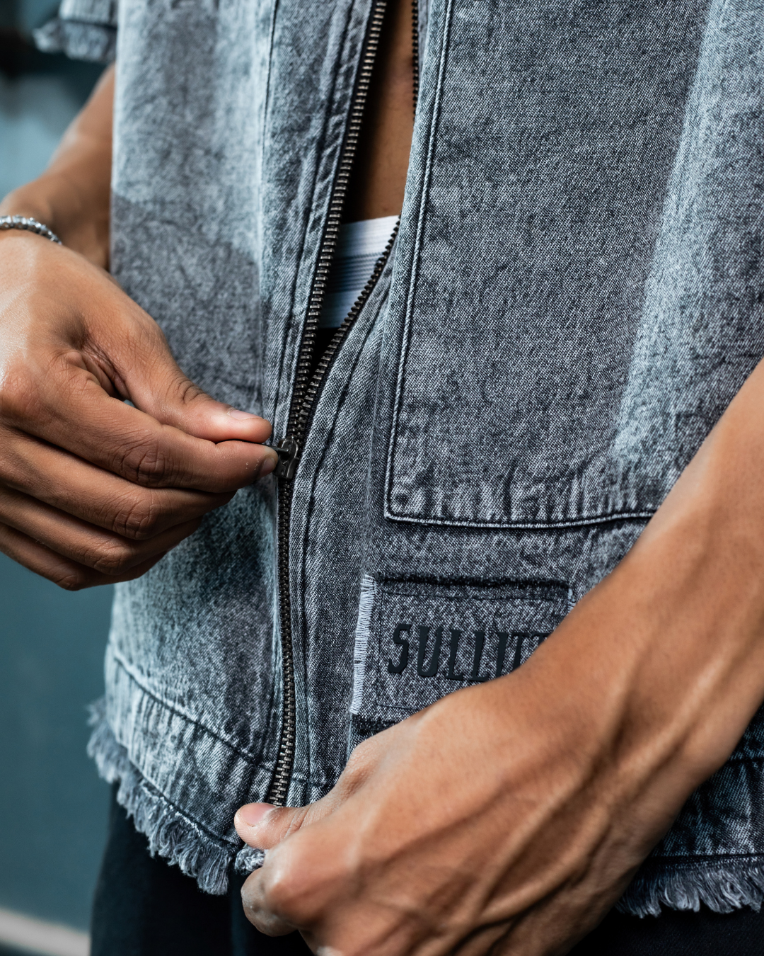 Denim zip-front jacket close-up with metal zipper and stitched logo patch