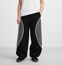 Black sweatpants with gray side panels, elastic waistband, relaxed wide-leg fit