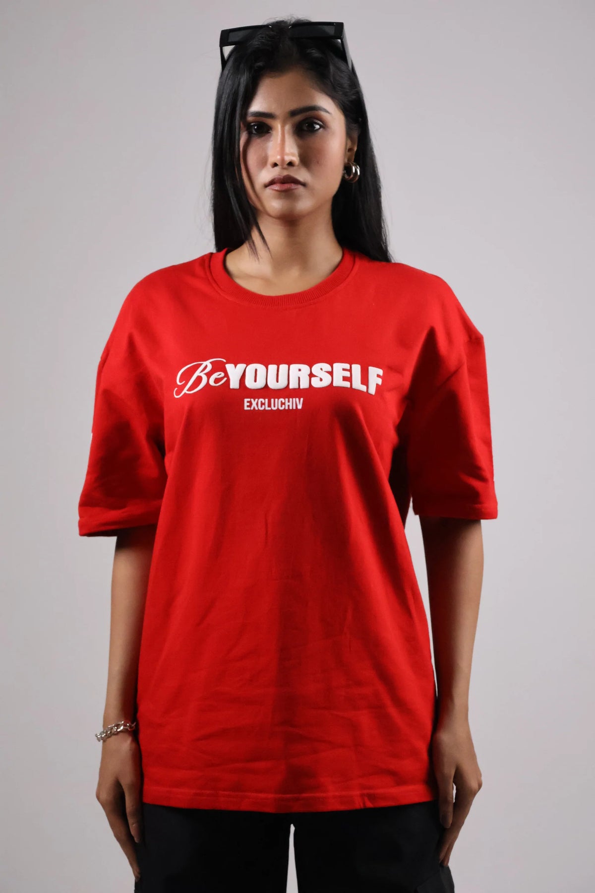 Red oversized T-shirt with front script logo and small text below.