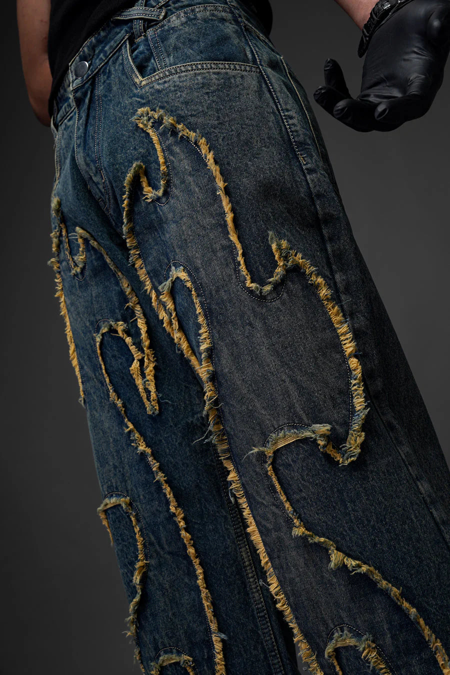Blue denim jeans with gold chainlike embroidered distress across the legs, straight fit.