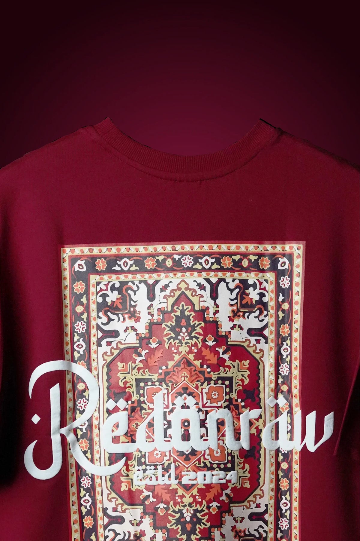 Crimson red T-shirt front view with centered ornate square Arabic graphic