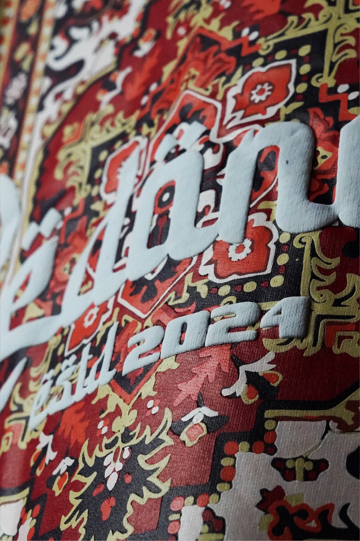 Crimson red T-shirt close-up of colorful ornate Arabic graphic with white lettering