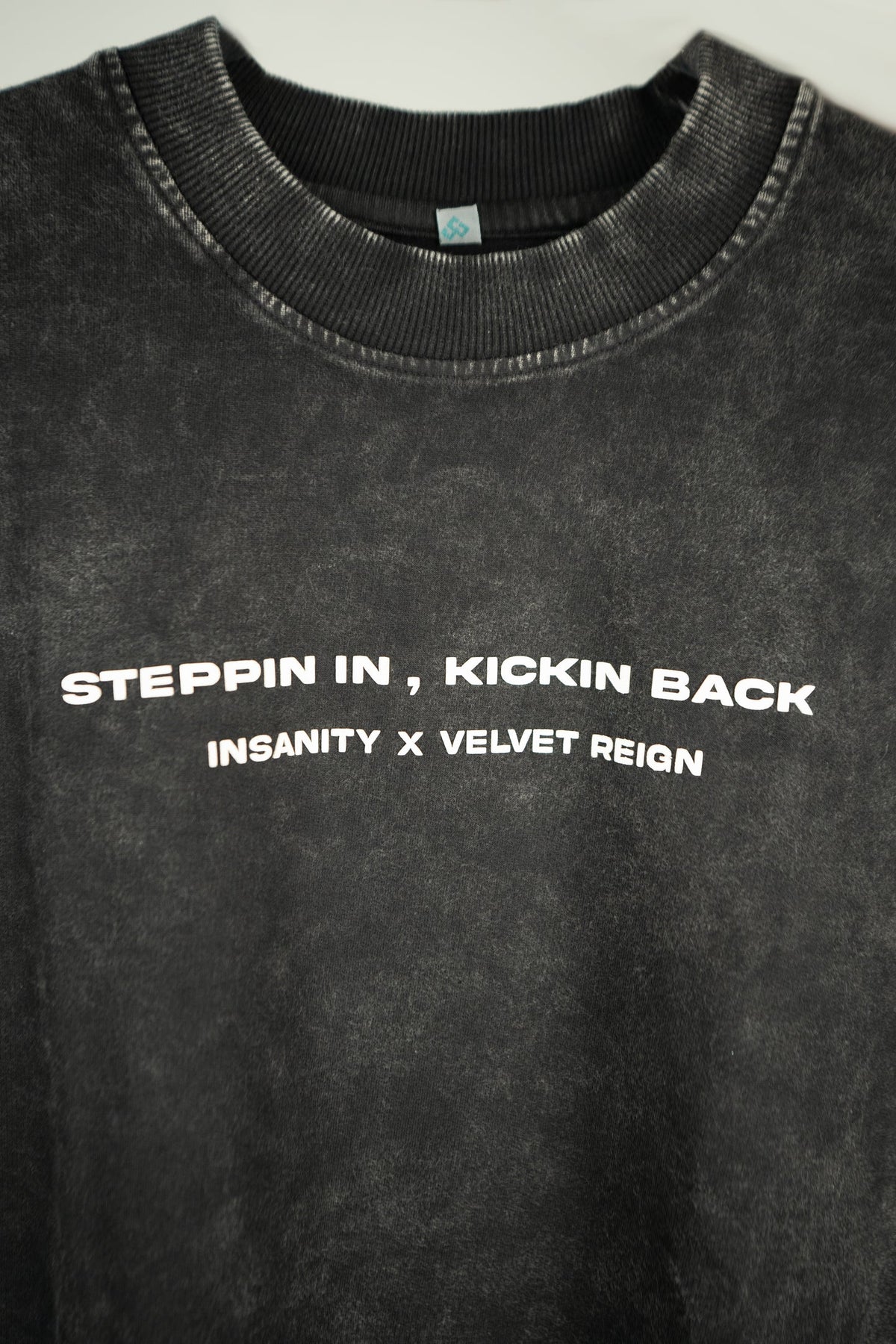 Black crew-neck T-shirt with "Steppin in, Kickin back" front graphic