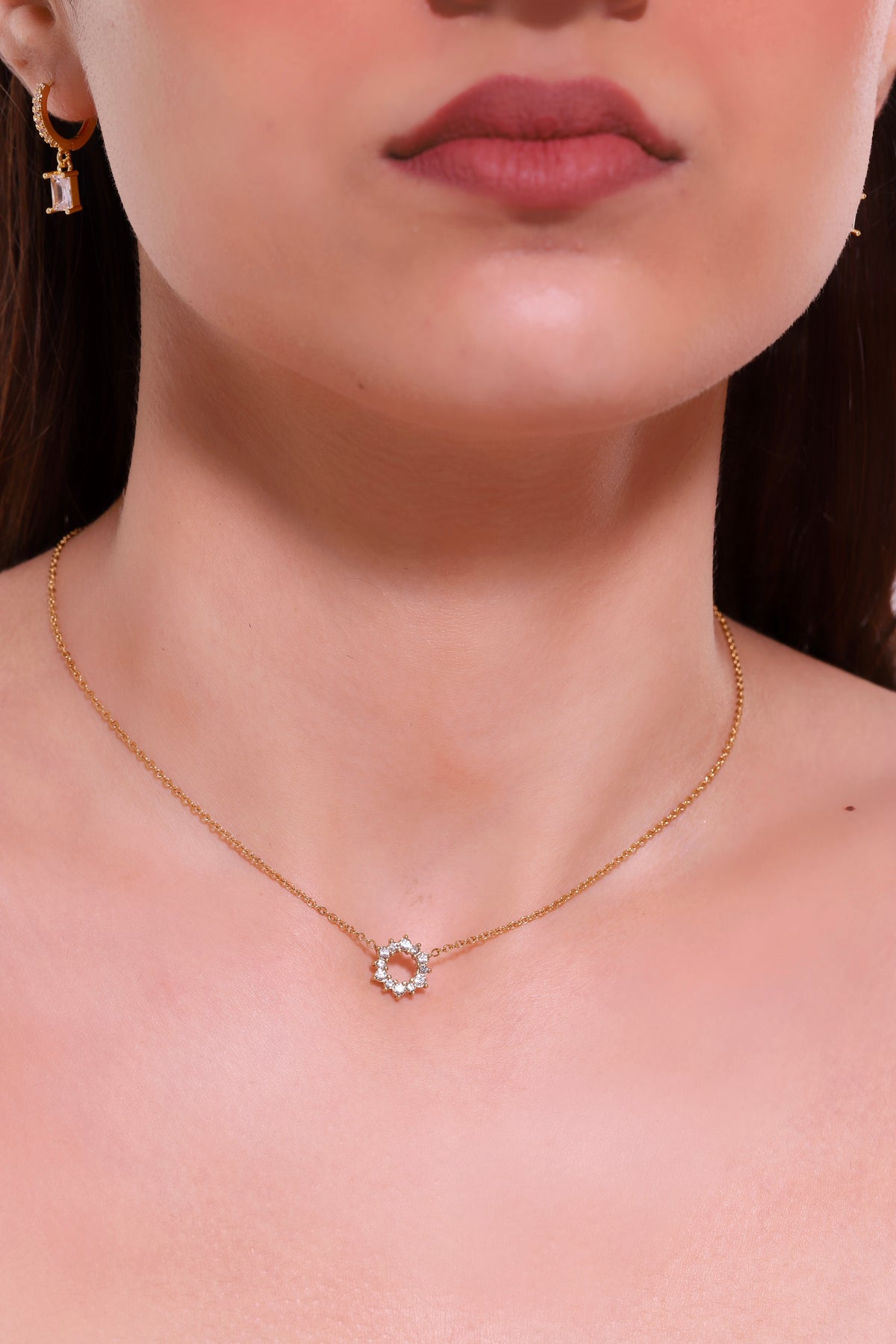 Gold chain necklace with round halo pendant centered at neck