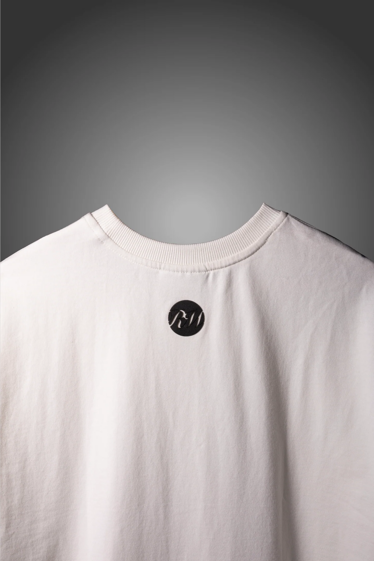 White crew-neck T-shirt with small black circular logo near the collar