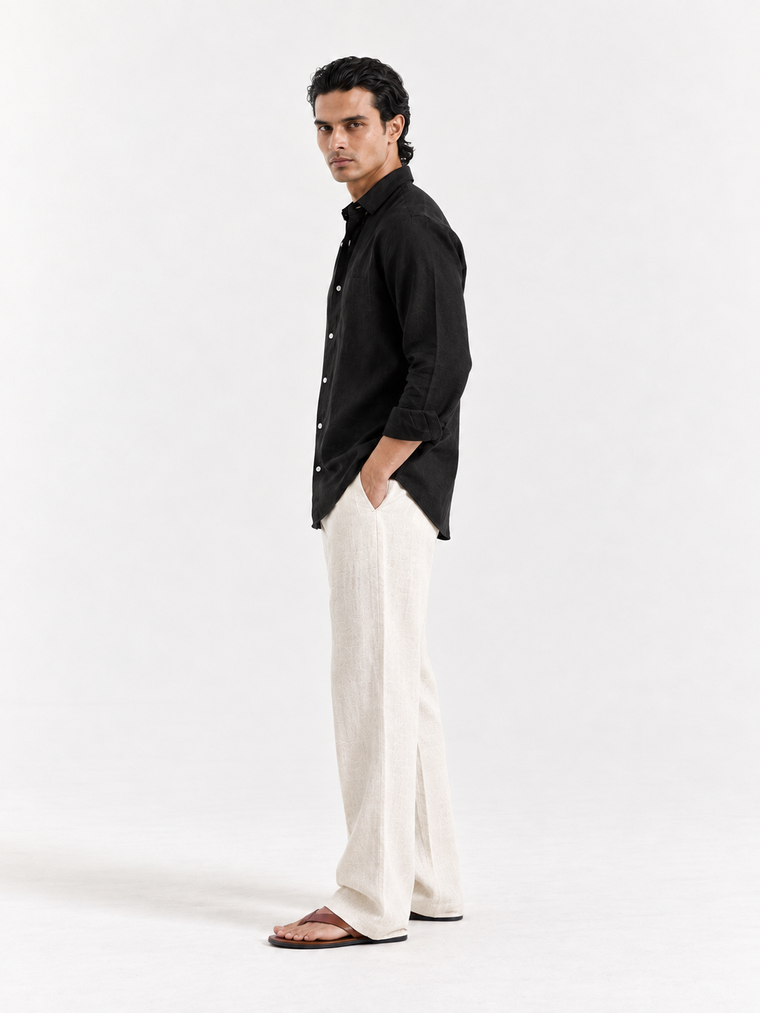Black linen button-up shirt with collar and white button placket, side view.