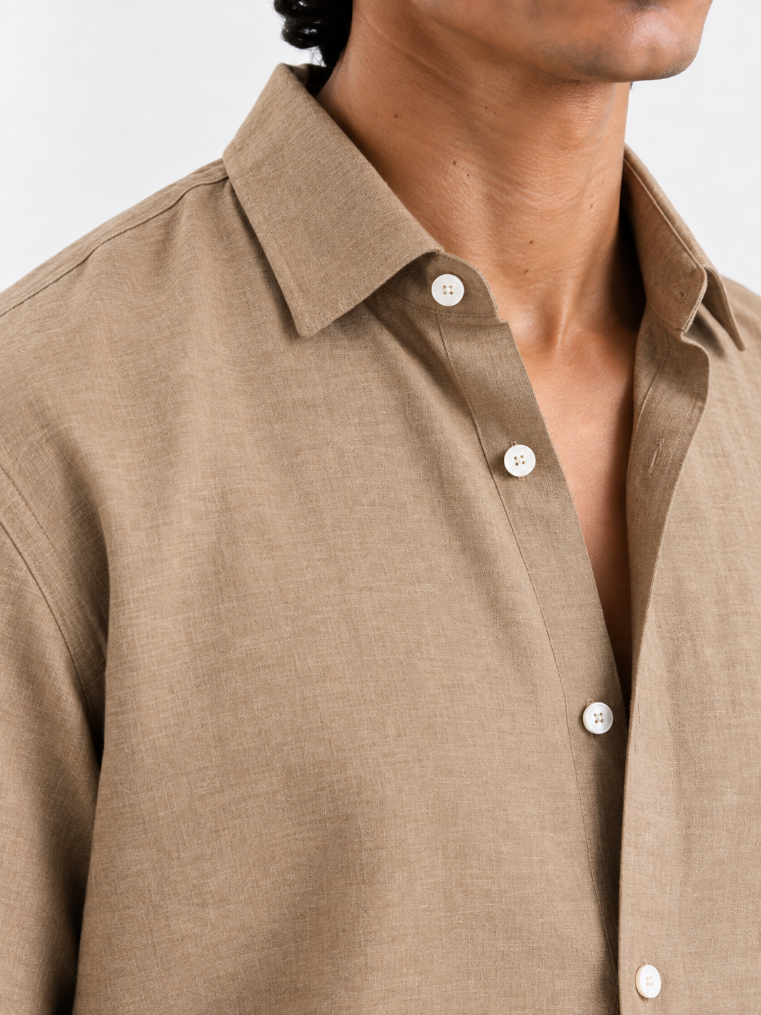 Tan linen shirt close-up: point collar and white buttons with stitched placket