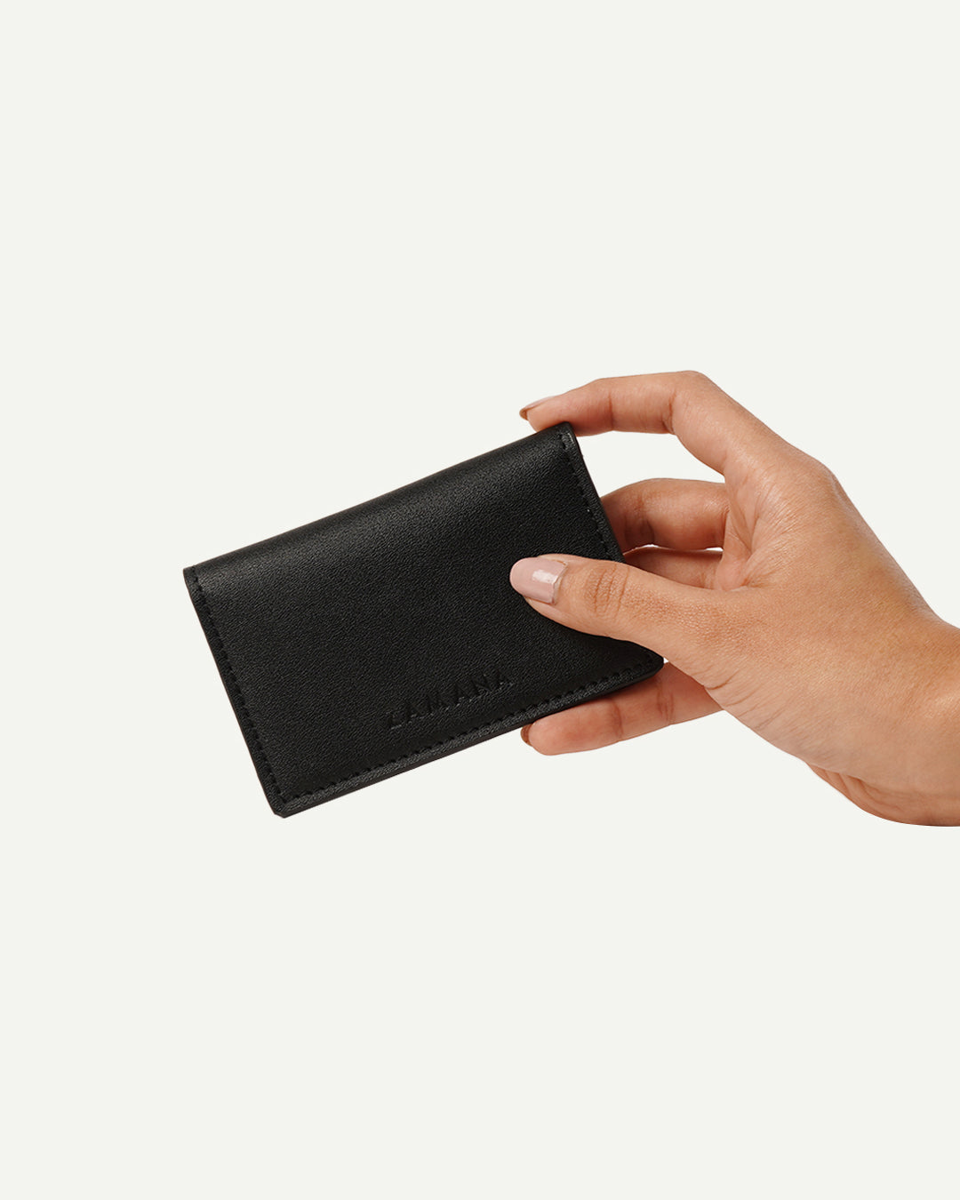 Black leather card holder with LAMAANA logo, held in hand