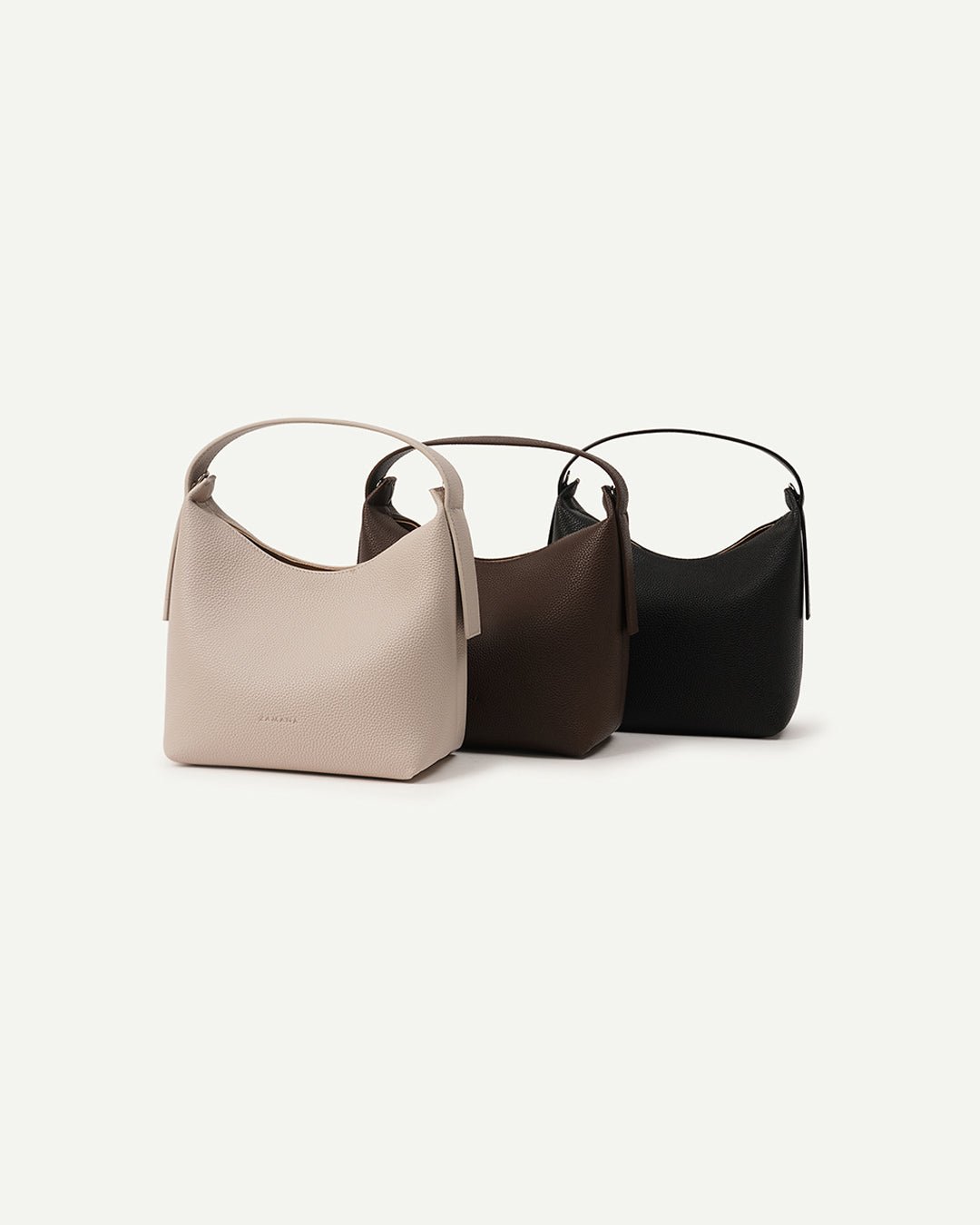 Small handbags in cream, dark brown, and black; curved top handles, open top