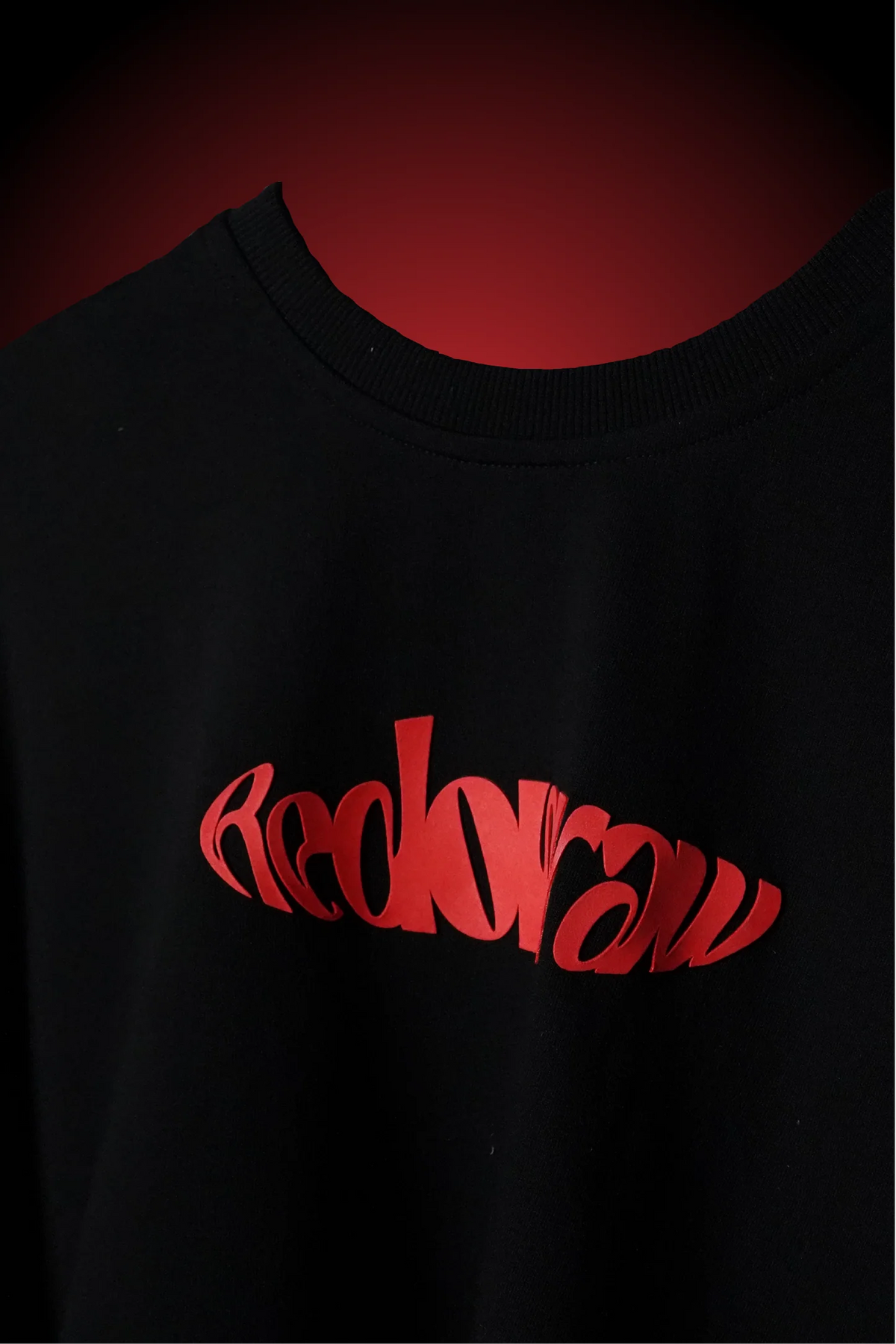Black crewneck T-shirt with red cursive graphic across the chest.