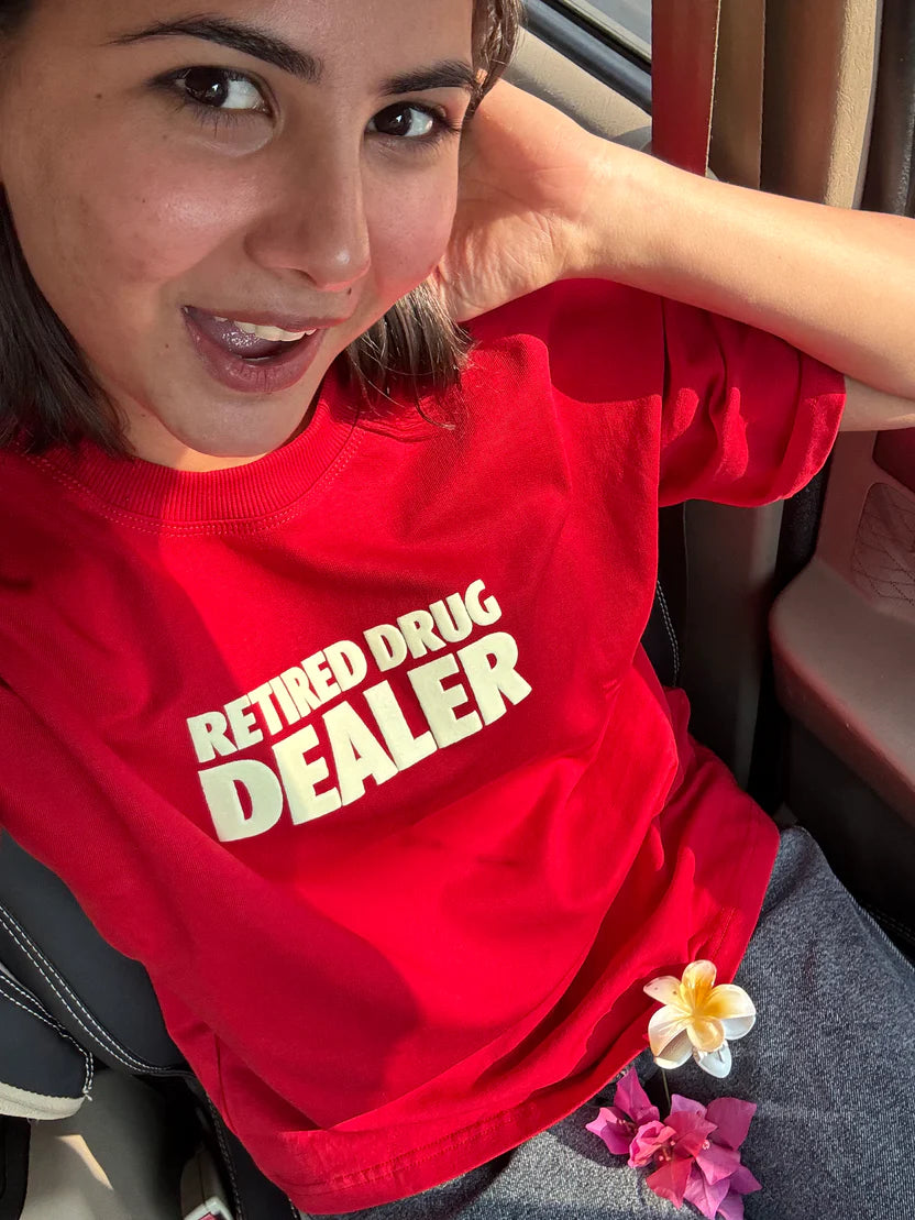 Red graphic T-shirt with bold “RETIRED DRUG DEALER” print across chest