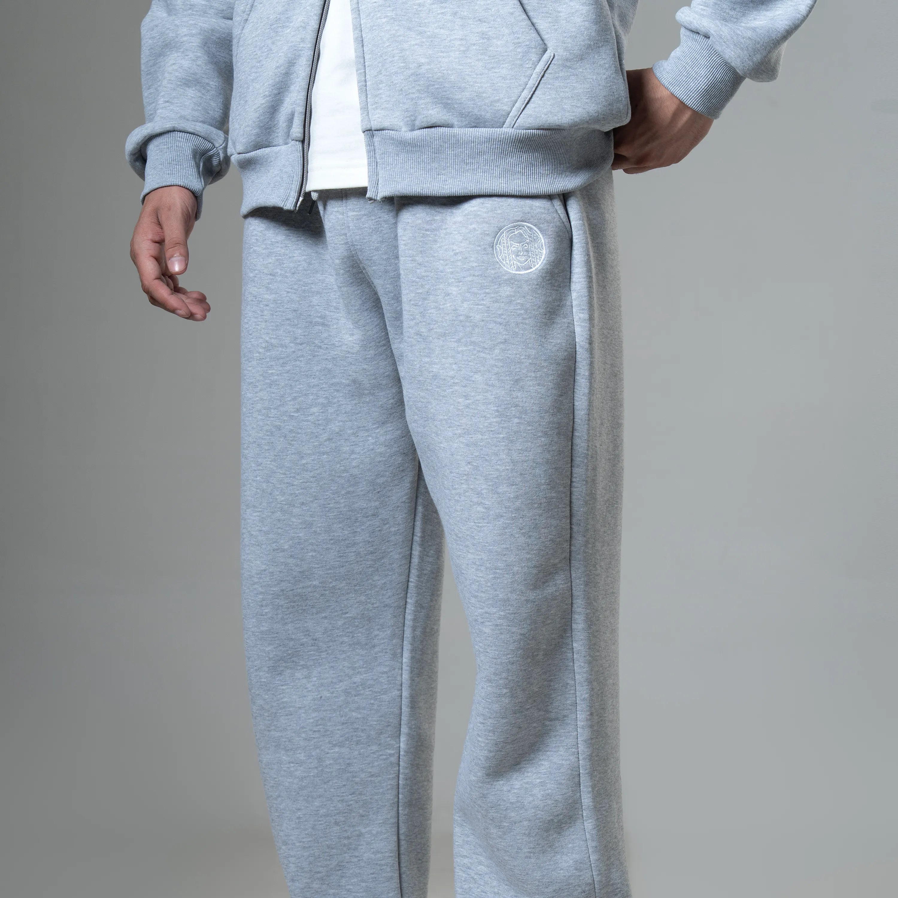 Person wearing gray sweatpants with a logo on a plain background