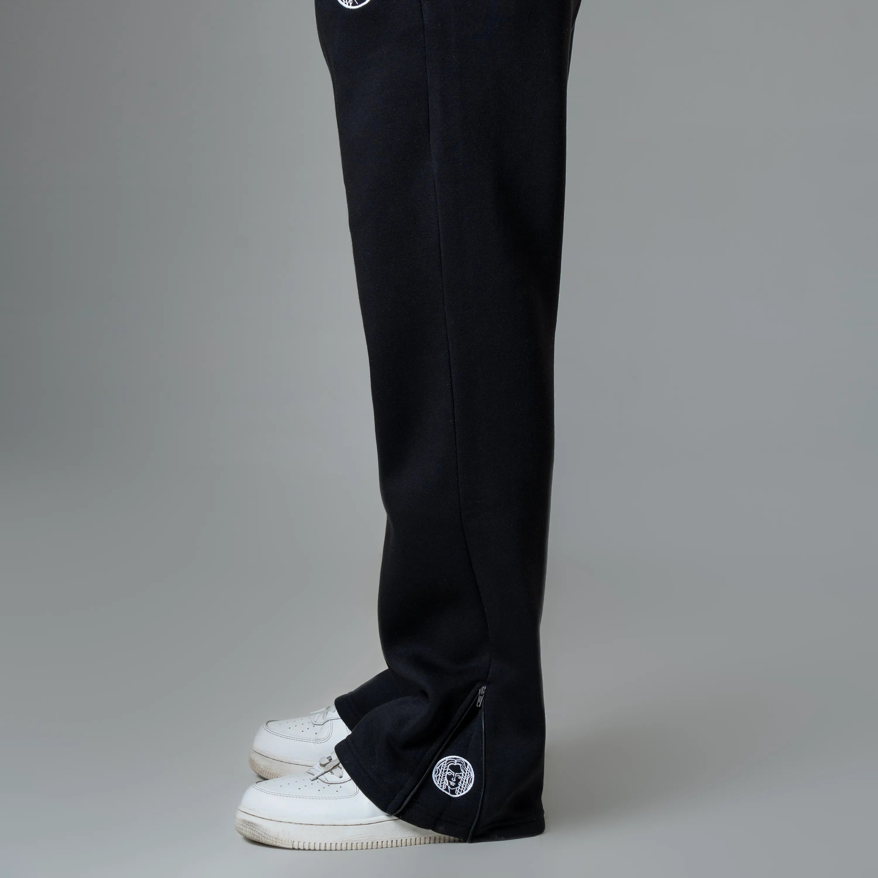 Person wearing black pants with white patches on a gray background