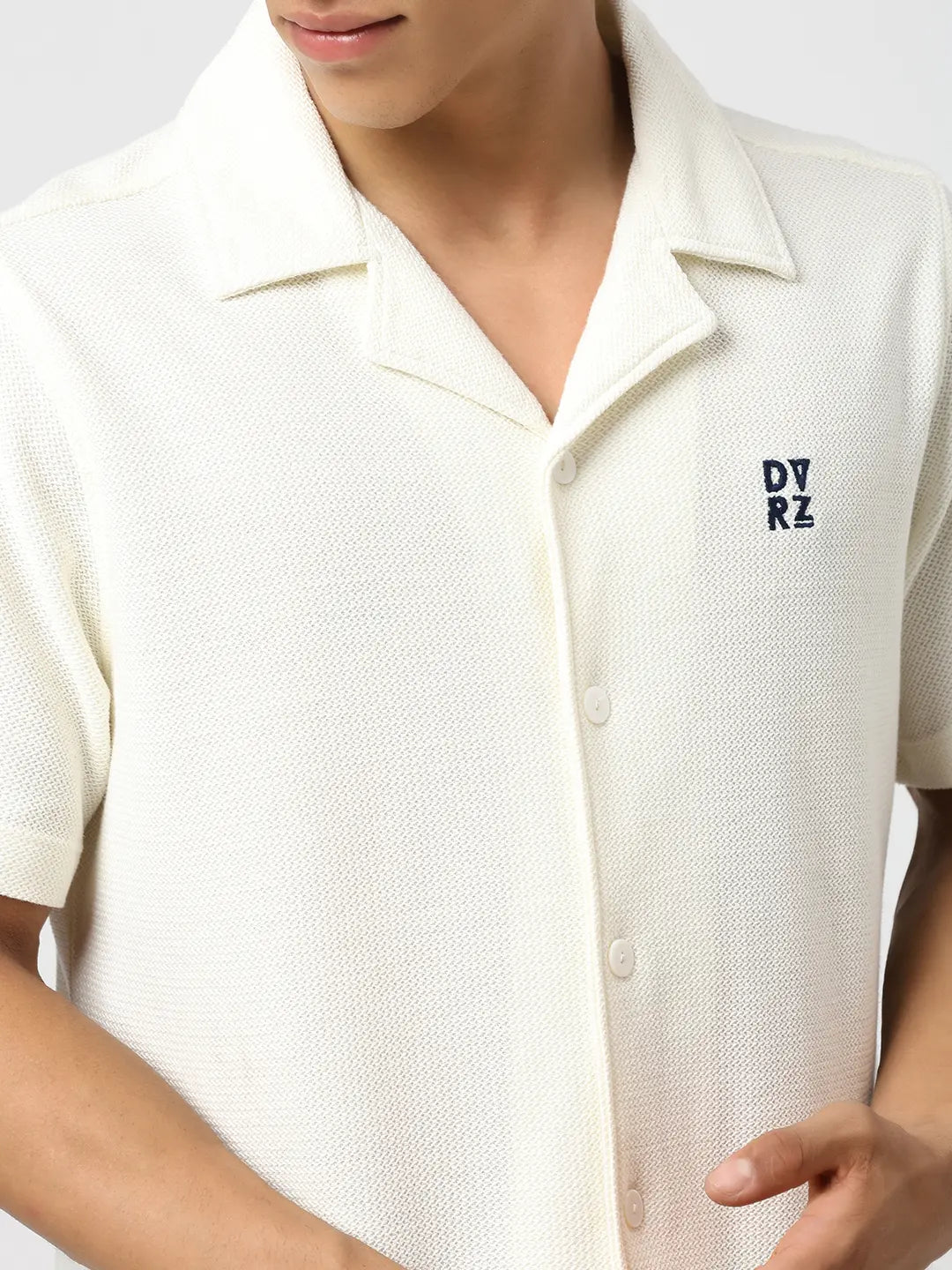 Ivory textured bowling shirt close-up: buttoned collar and small chest logo