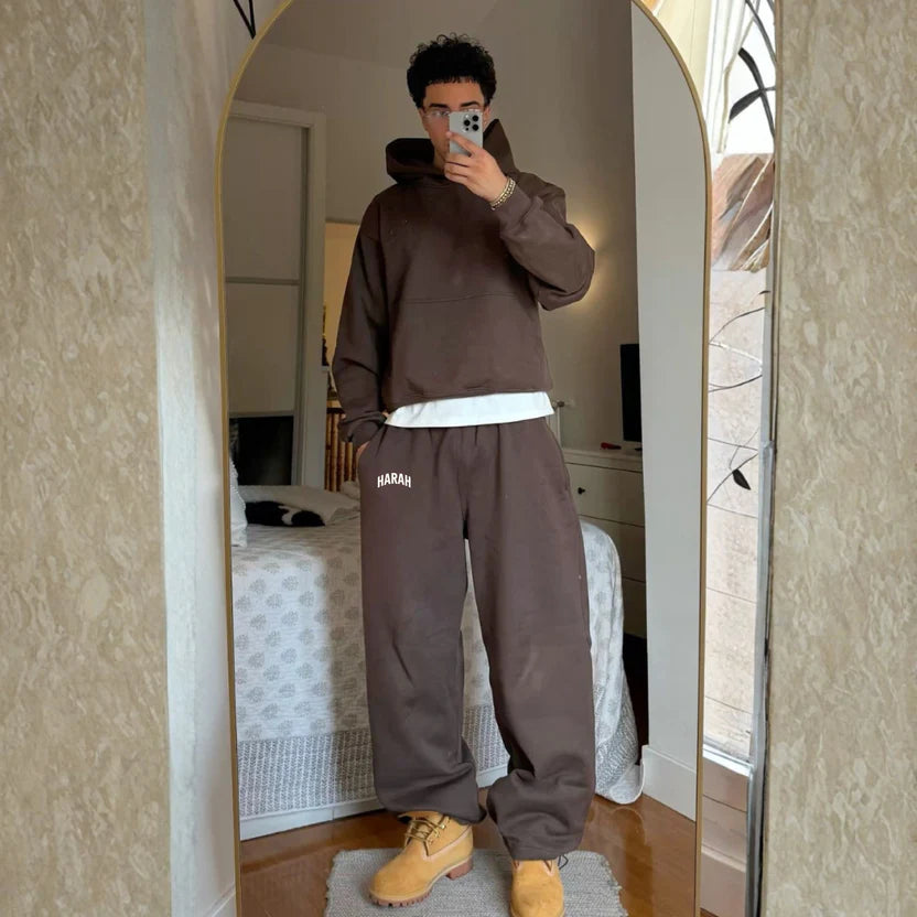 Brown sweatpants with elastic waistband and wide relaxed legs, front pocket patch detail