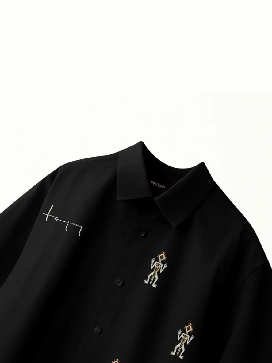 Black boxy fit button-up shirt with embroidered figures on the front placket
