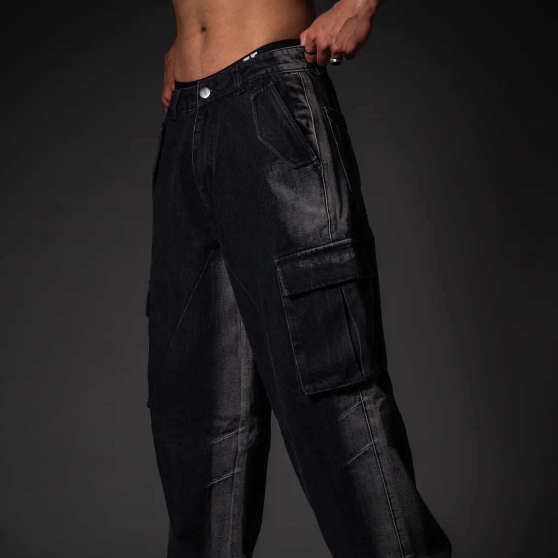 Black cargo pants worn by a person on a dark background