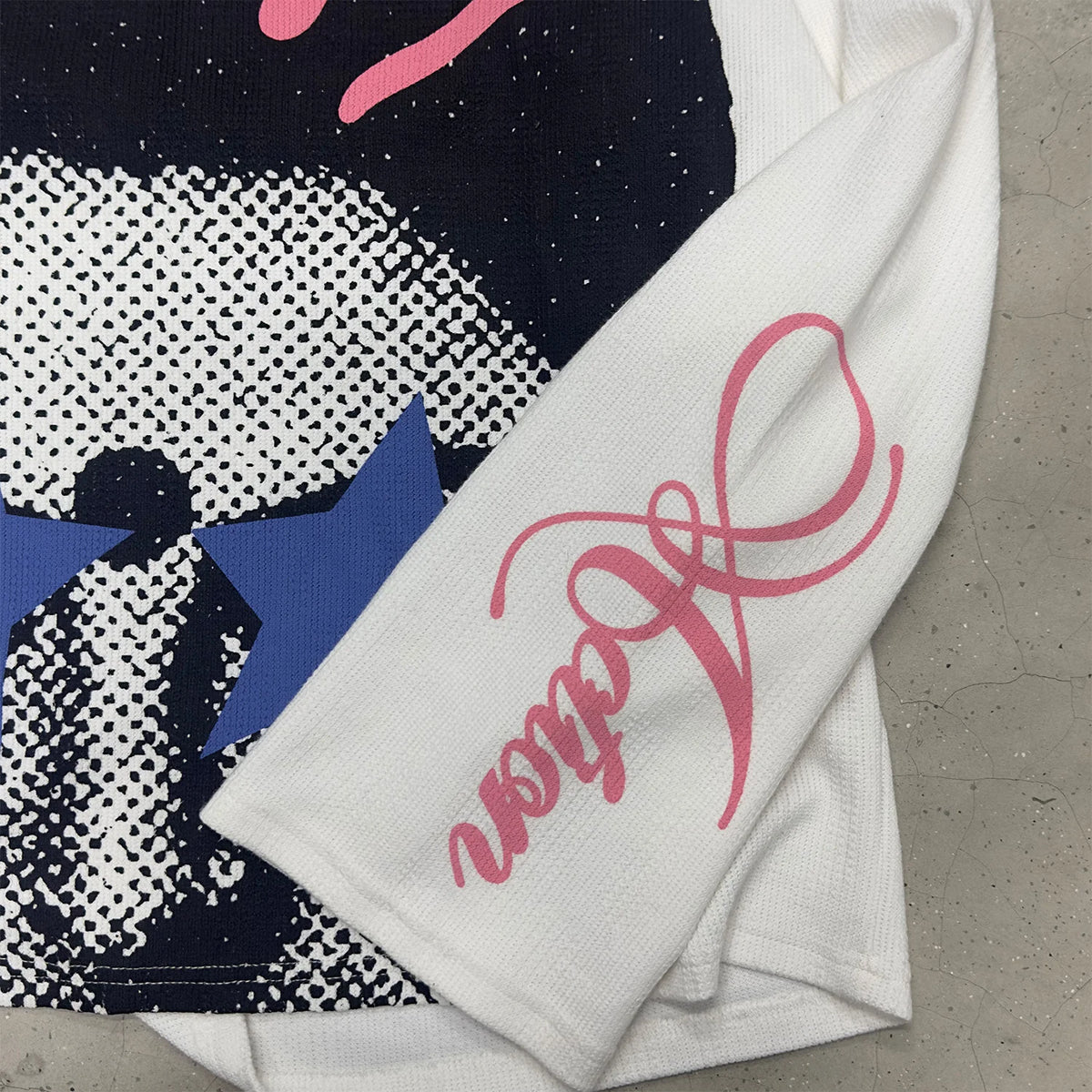 White long-sleeve T-shirt with pink script on sleeve and blue star graphic