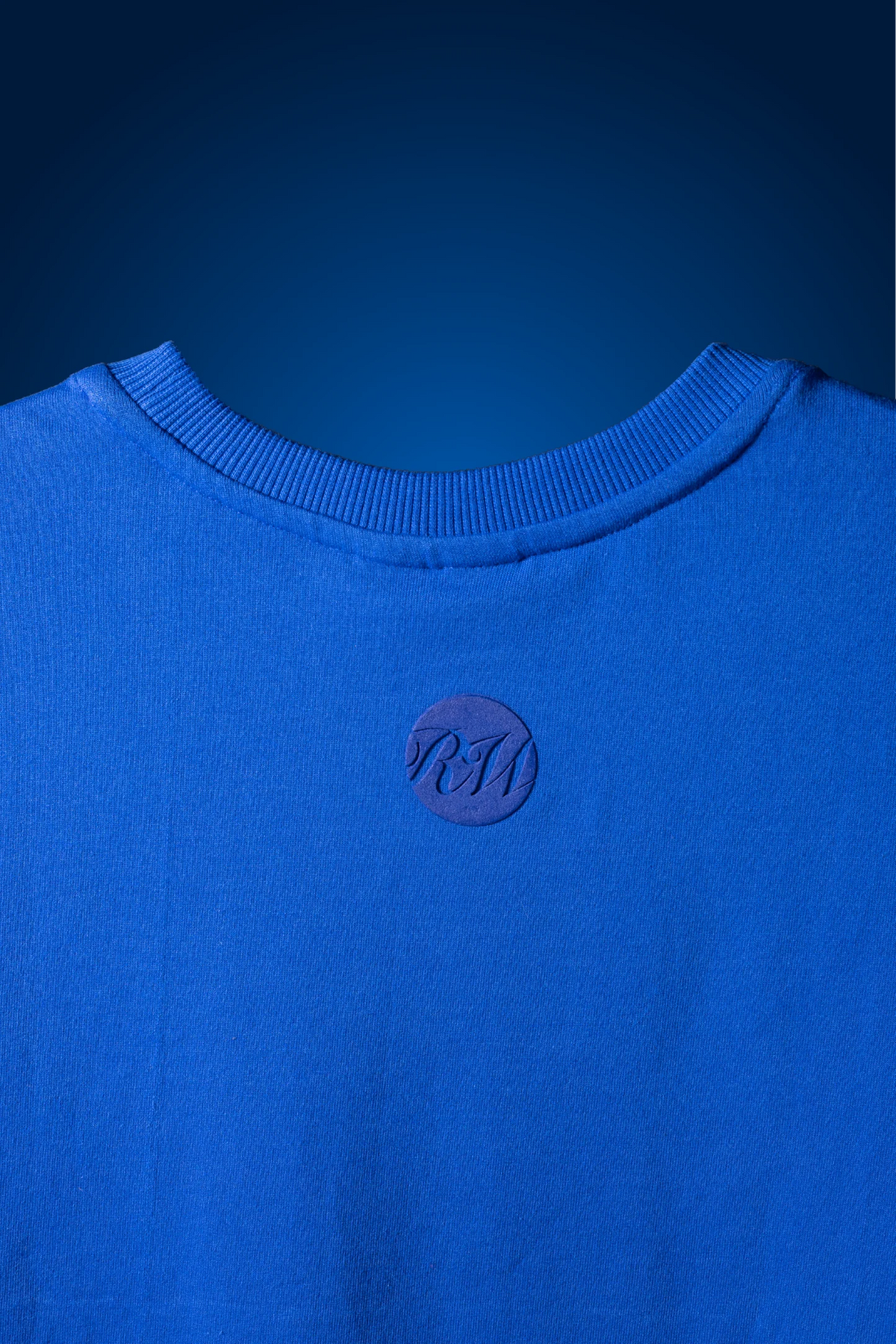 Blue crew-neck T-shirt with small circular chest emblem