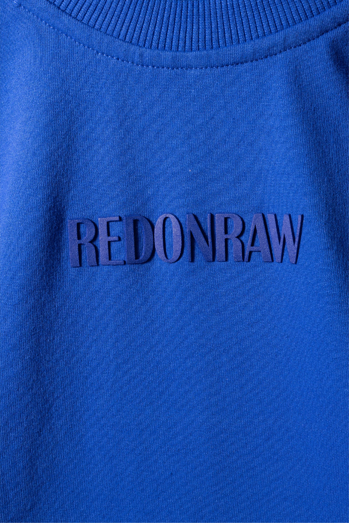 Blue knit T-shirt chest with REDONRAW logo text on fabric
