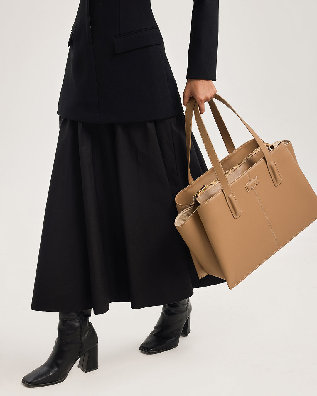 Caramel leather tote bag worn crossbody-style with double handles