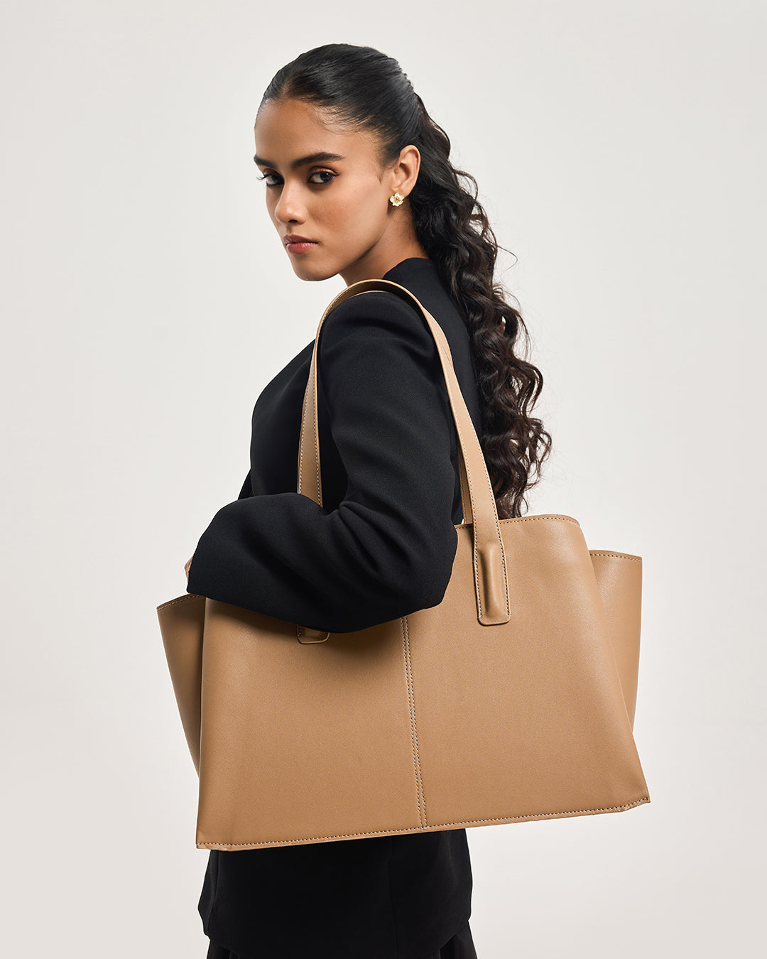 Caramel leather tote bag on model in side view with top handles