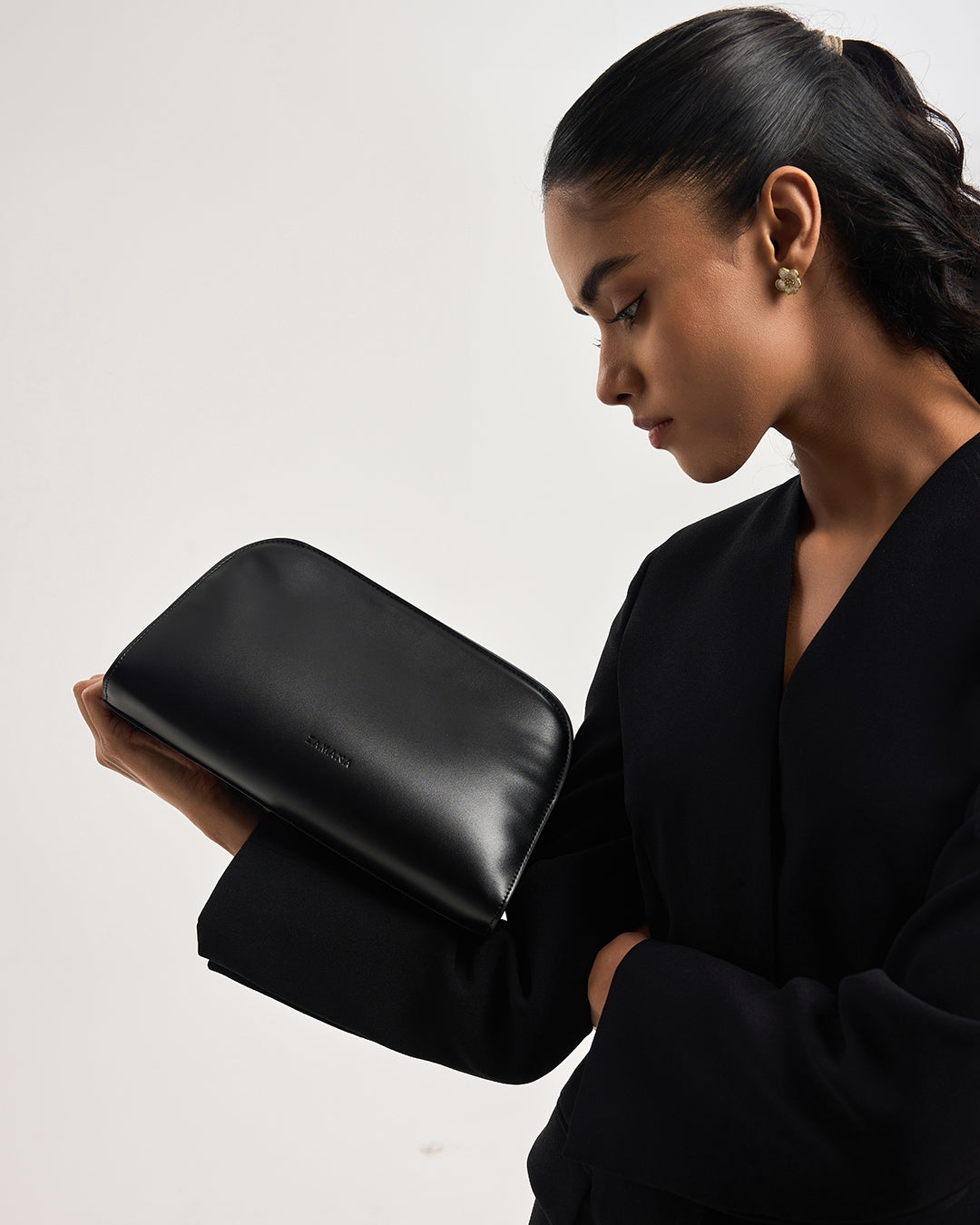 Black cosmetic pouch with zip closure, held in hand