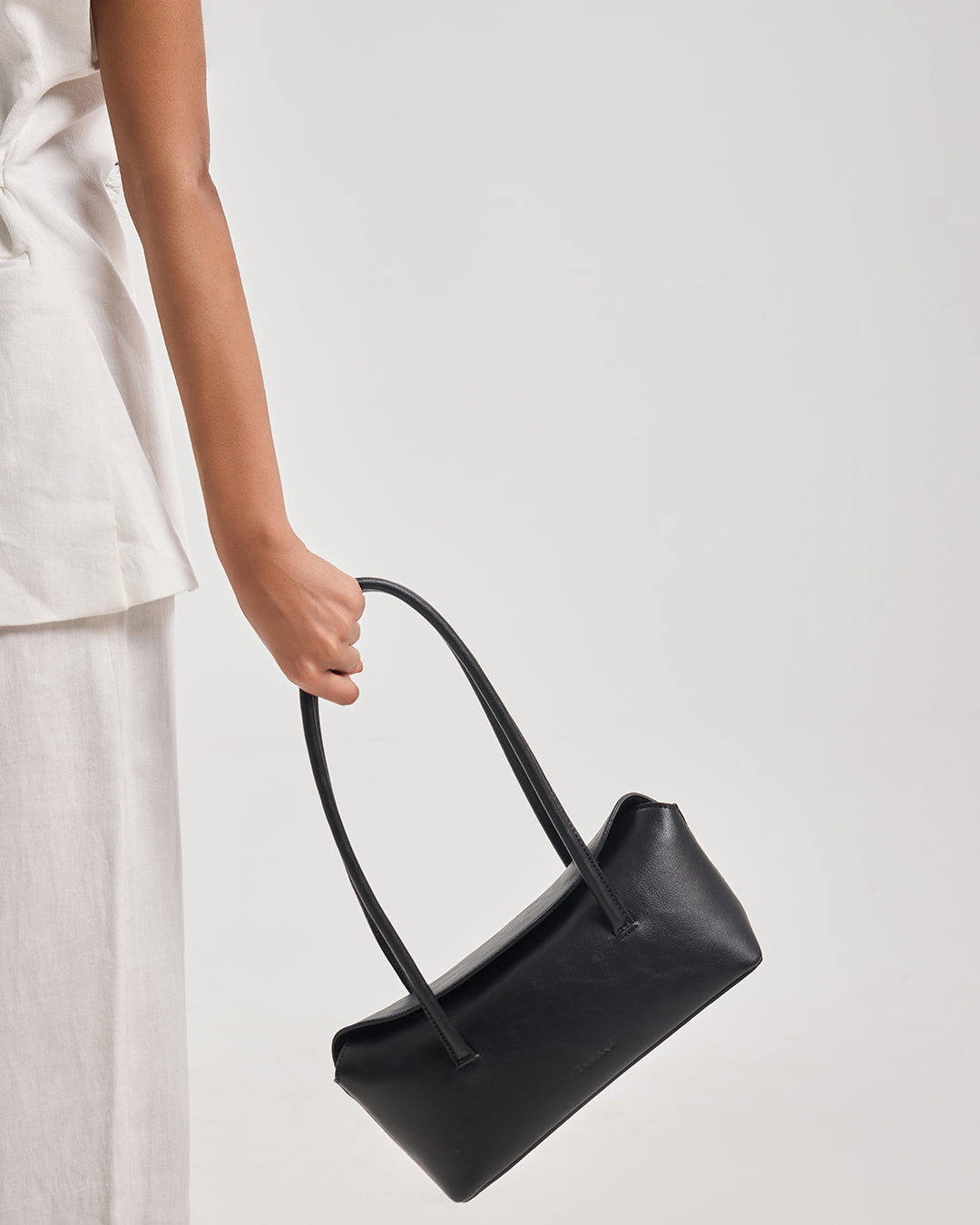 Black handbag with short handles, held by a person