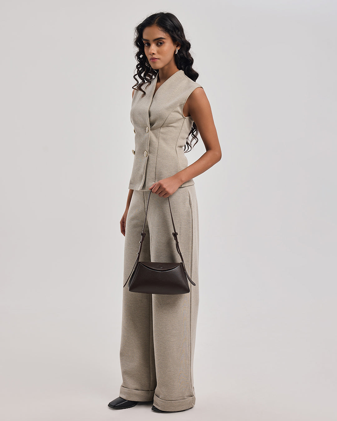 Dark brown leather shoulder bag on model with adjustable crossbody strap