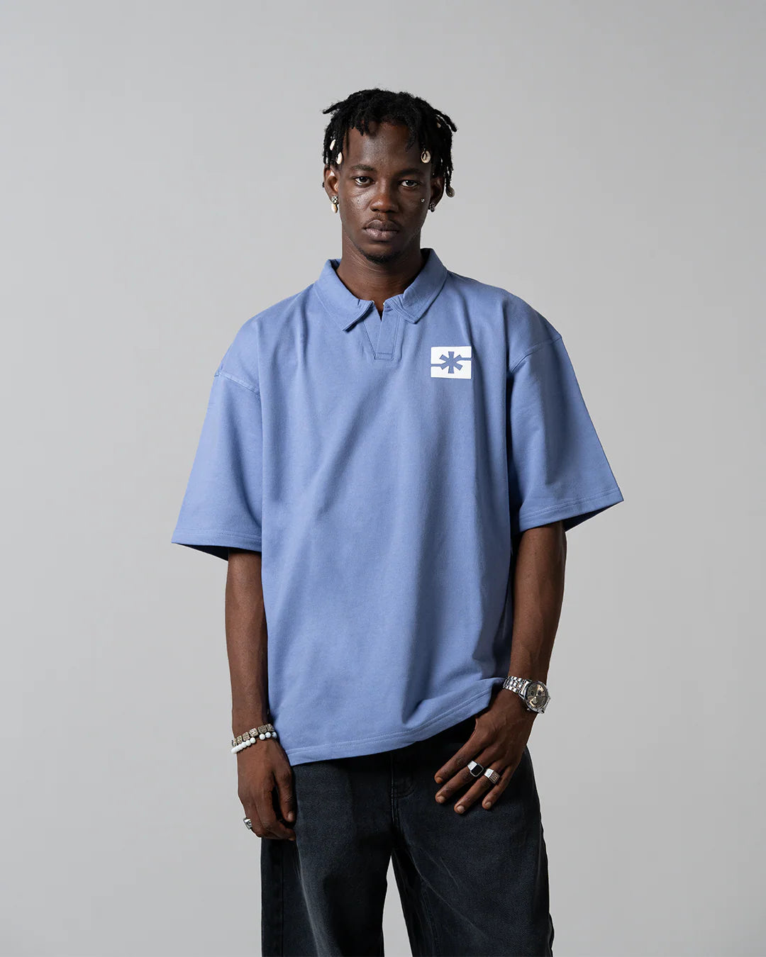 Light blue polo shirt with short sleeves, collar, and chest logo patch.