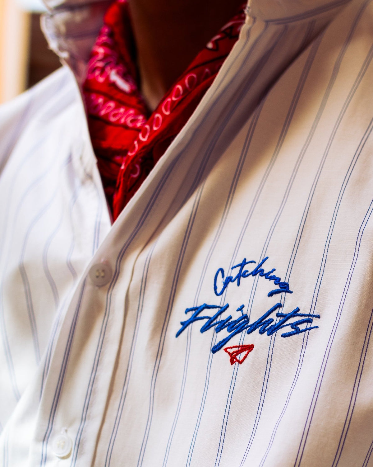 White pinstripe suiting shirt with blue vertical stripes and chest script logo