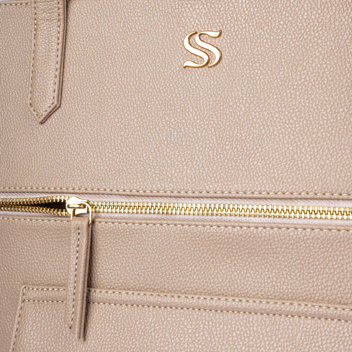 Almond-beige tote bag close-up with gold zipper and small S emblem