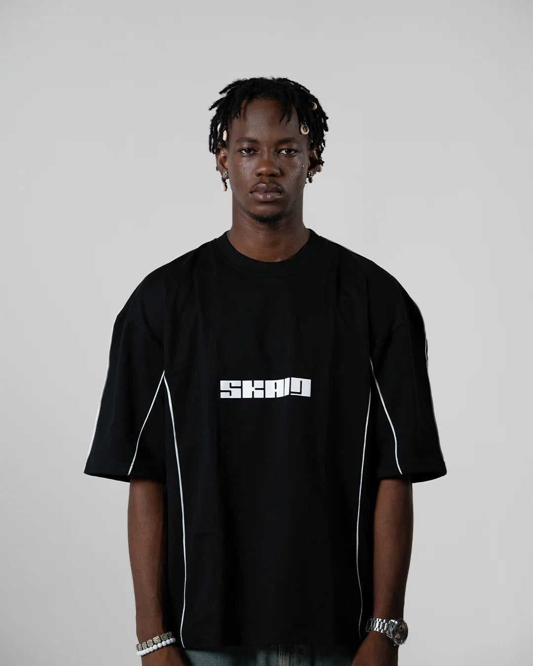 Black crewneck tee with white piping and SKAID chest logo.