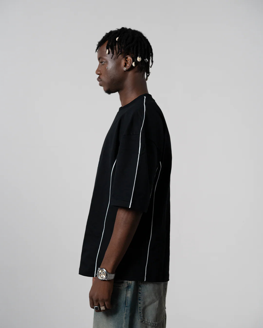 Black crewneck tee side view with white piping along sleeves and hem.