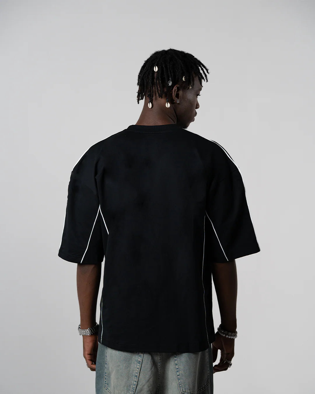 Black crewneck tee back view with white side piping.