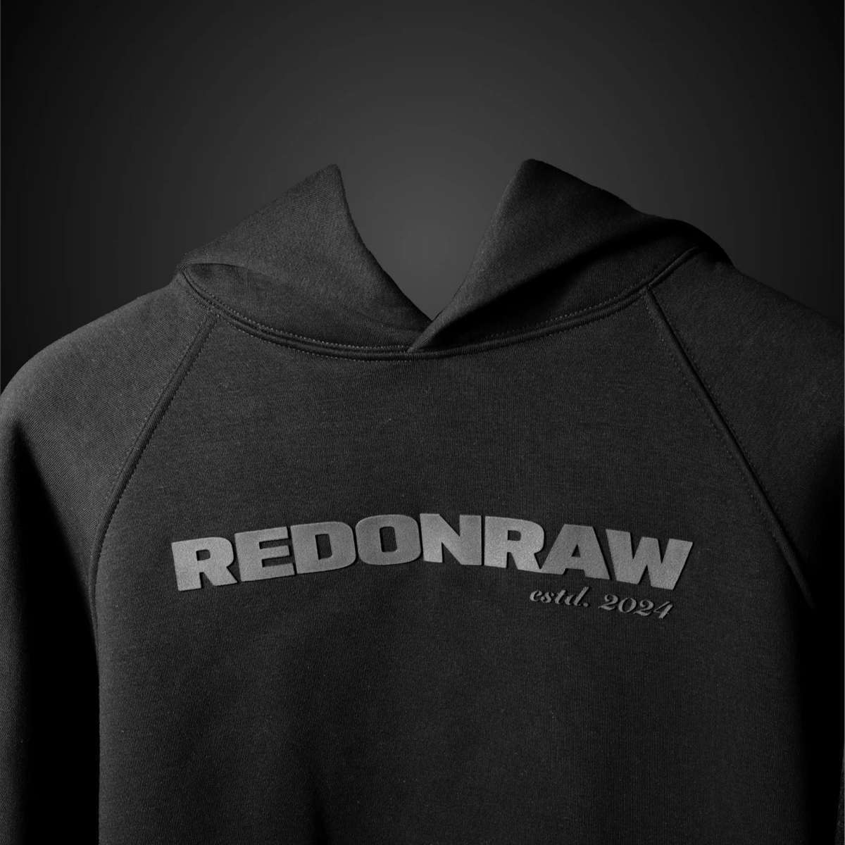 Charcoal black hoodie chest logo: REDONRAW with small est. 2021 text