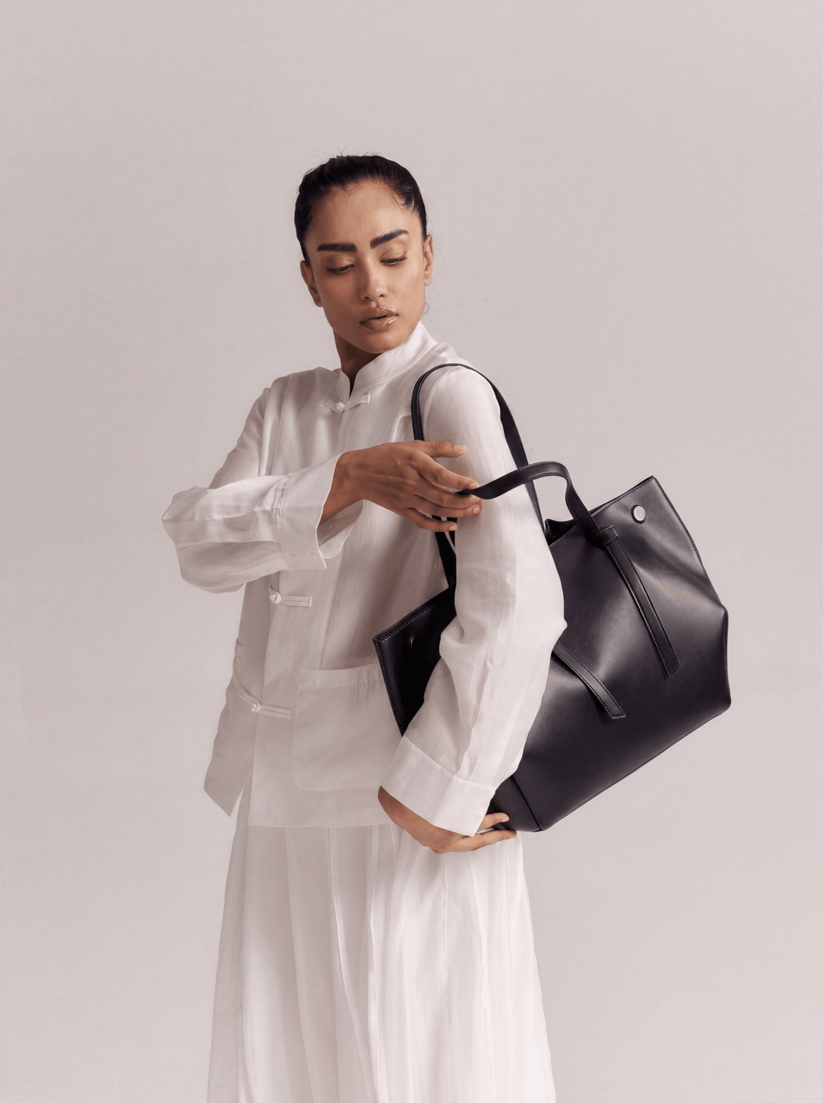 Large black tote bag held by the top handles, wide gusseted shape