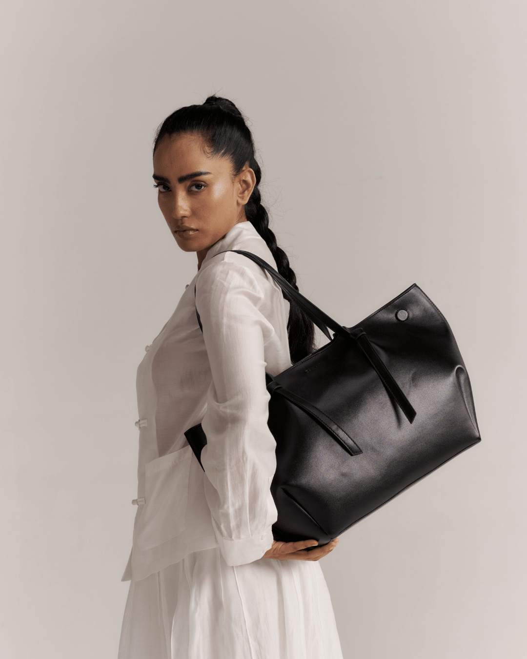 Black large tote bag worn over the shoulder, structured top and handles