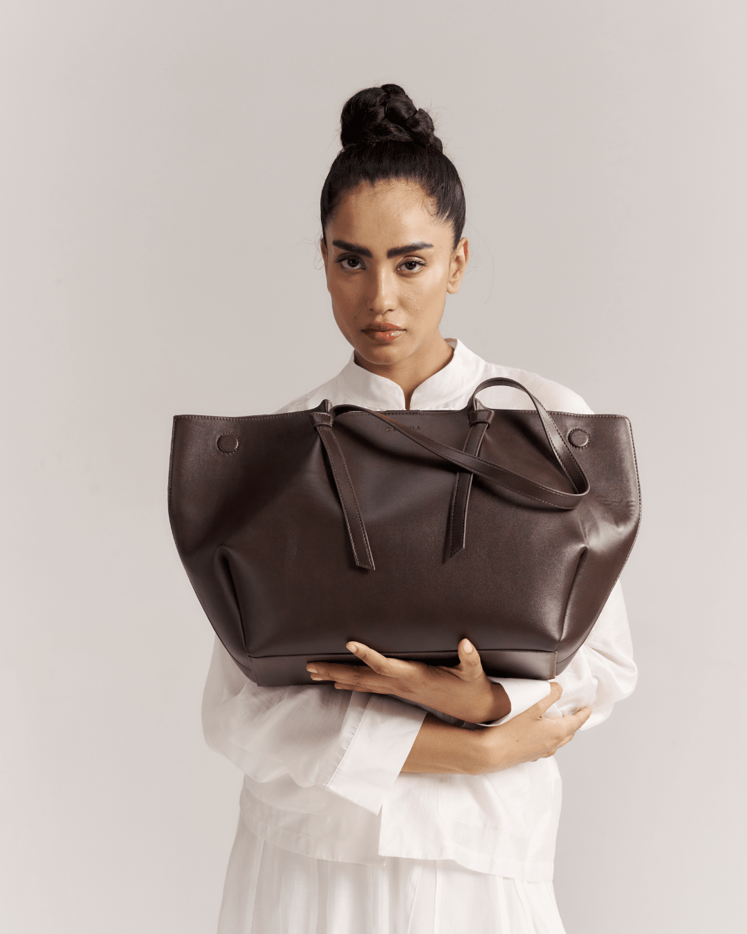 Brown leather tote bag with bow-tie straps and wide open top, front view