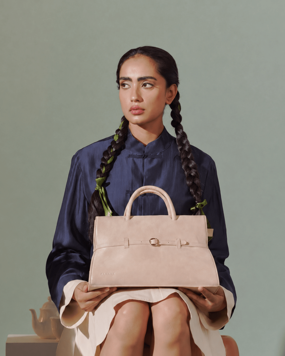 Cream handbag tote with top handles and front buckle strap, held by model