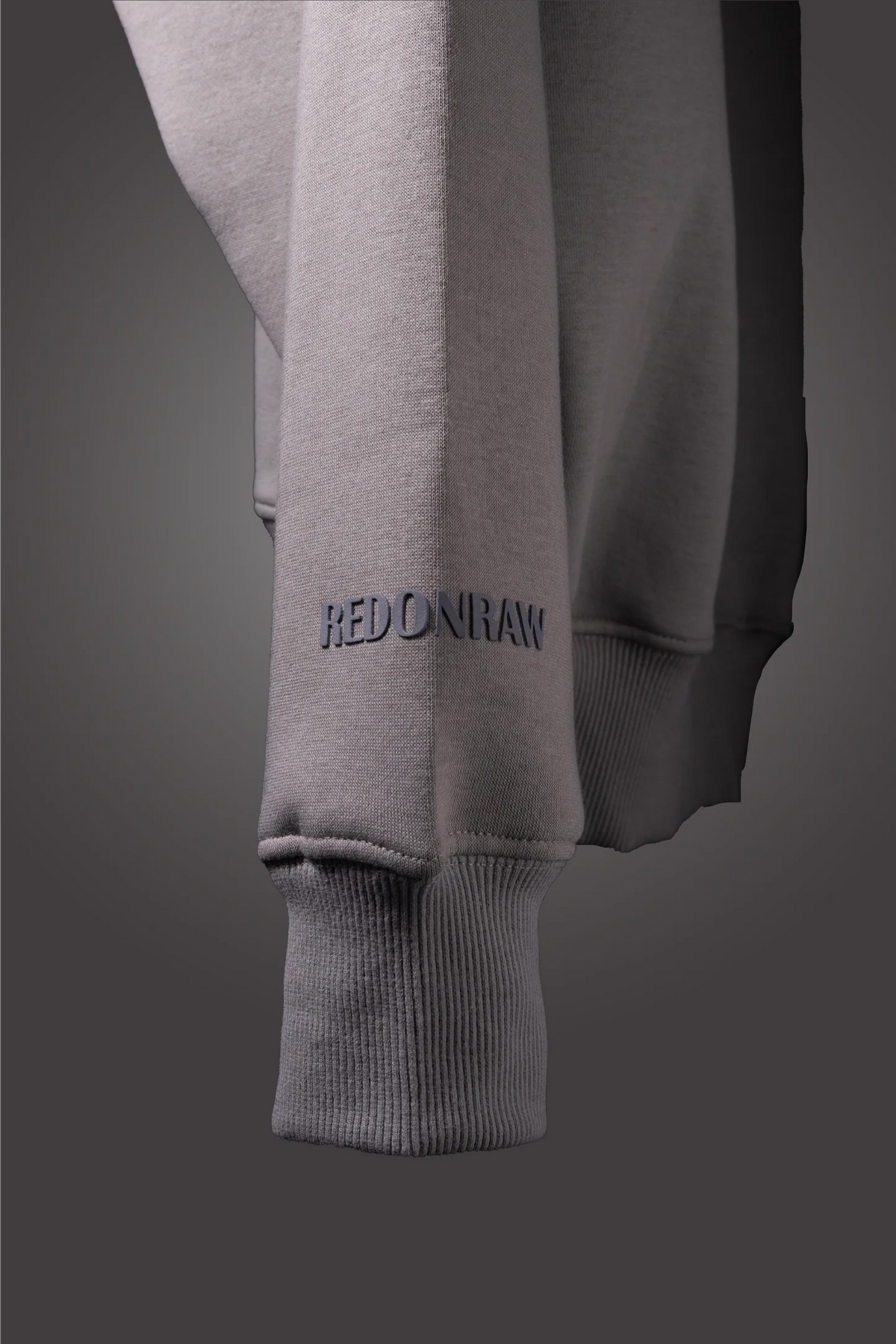 Light gray hoodie sleeve with ribbed cuff and small logo on lower arm