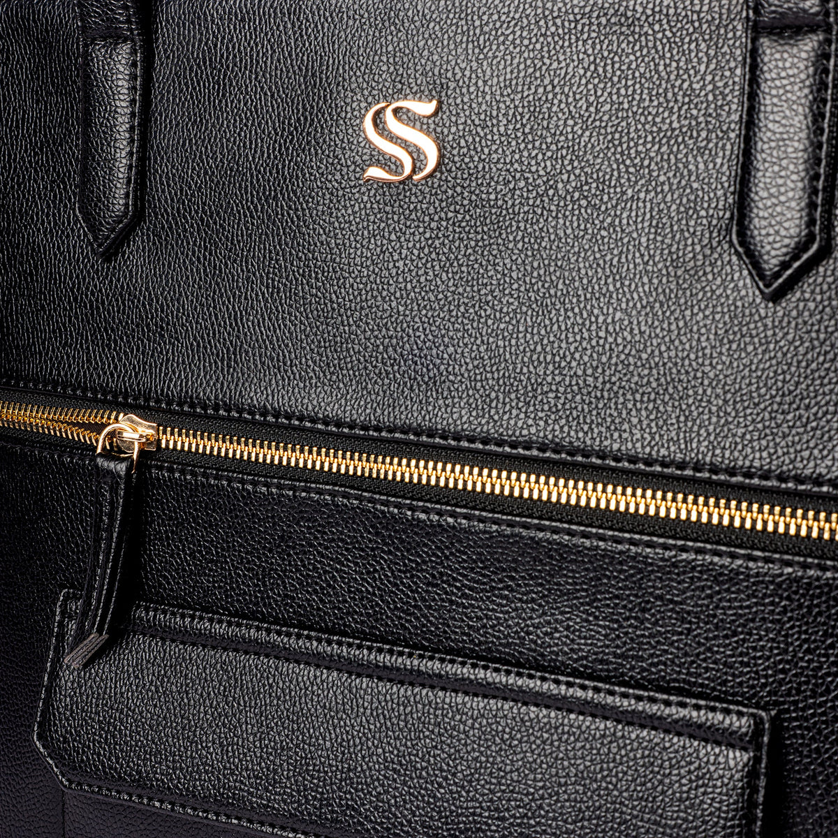 Charcoal faux-leather tote bag with gold zipper detail and embossed monogram S on front