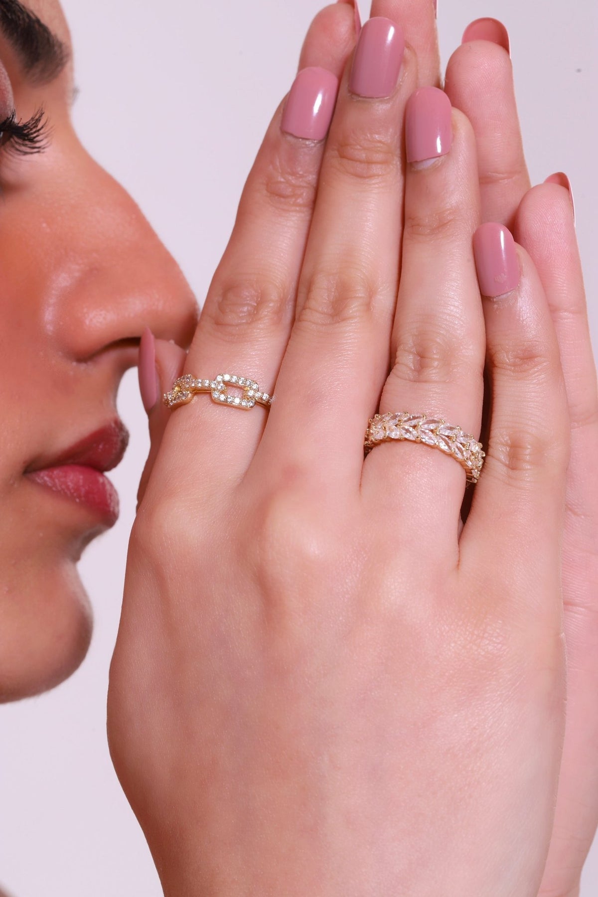 Gold-toned gemstone band rings with clear stones on fingers