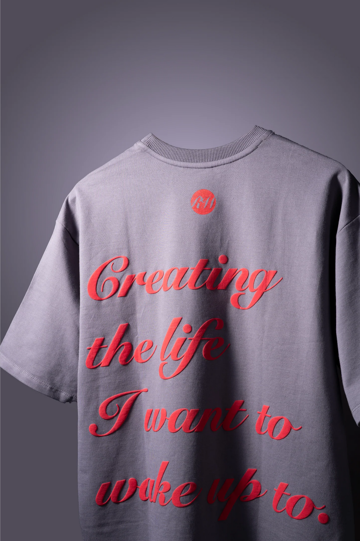 Light gray T-shirt with red script 'Creating the life...' and small chest logo