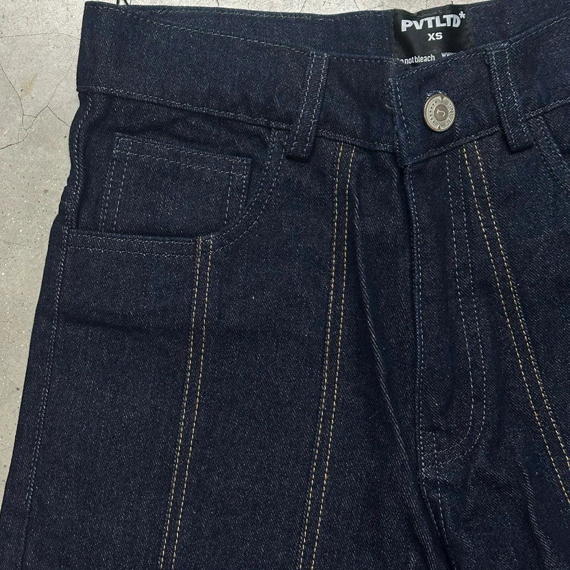 Dark blue denim jeans waistband close-up, logo patch, button fly, contrast yellow stitching
