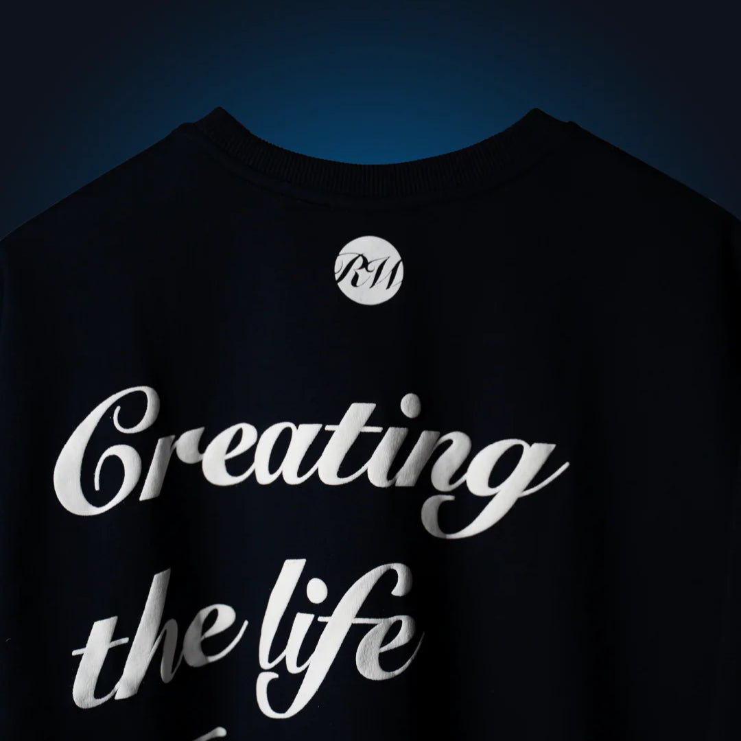 Navy blue graphic crewneck T-shirt with 'Creating the life' script and circular RW logo